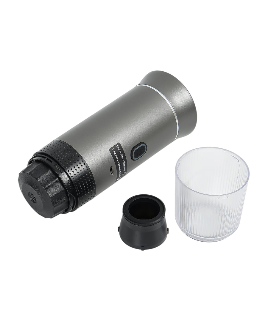 Gray portable espresso maker disassembled showing main unit, black capsule adapter, transparent collection cup, and detachable components"
